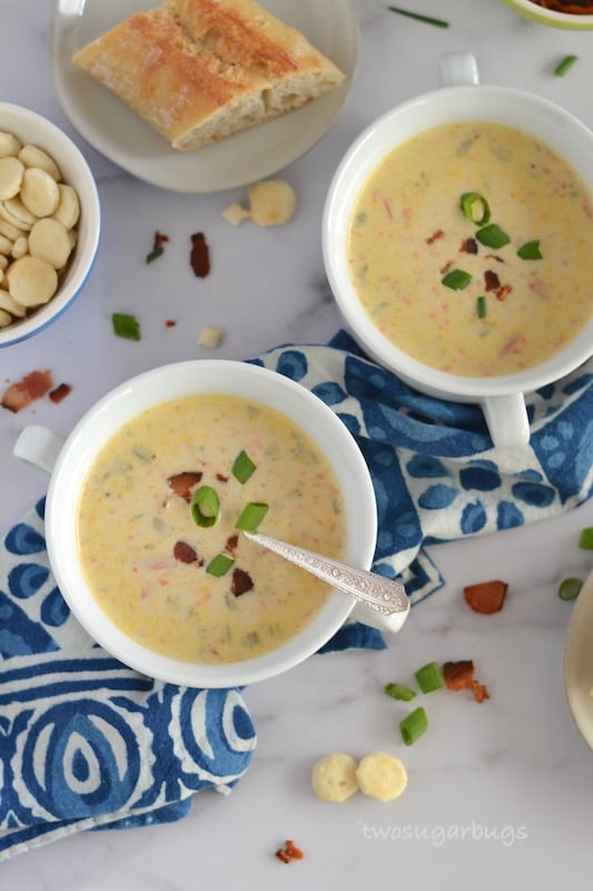 two bowls of chowder on a napkin with a slice of bread in the background