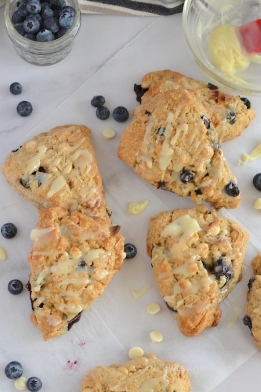 A pile of scones, blueberries and white chocolate on parchment paper