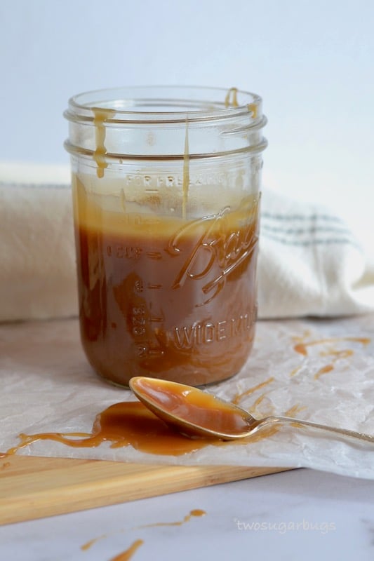 Mason jar of caramel sauce with a messy spoon in front