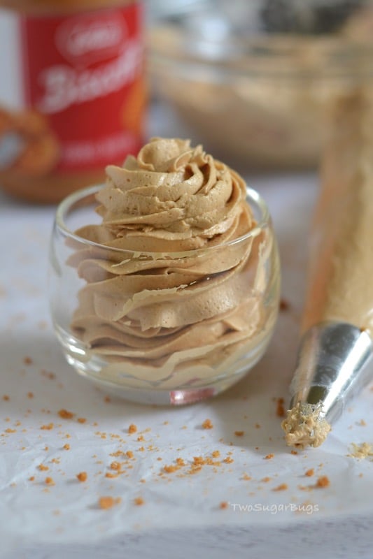 Piped cookie butter frosting in a glass with a piping bag next to it