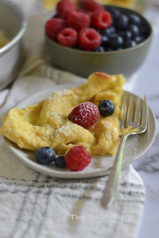 Dutch Baby on a plate with fresh berries in the background