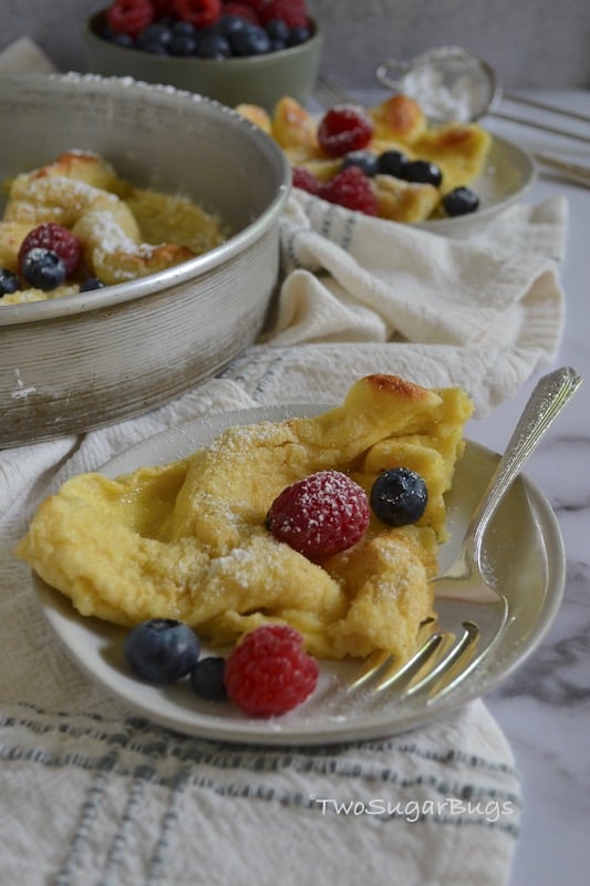 Slice of Dutch Baby with berries on a plate with a fork