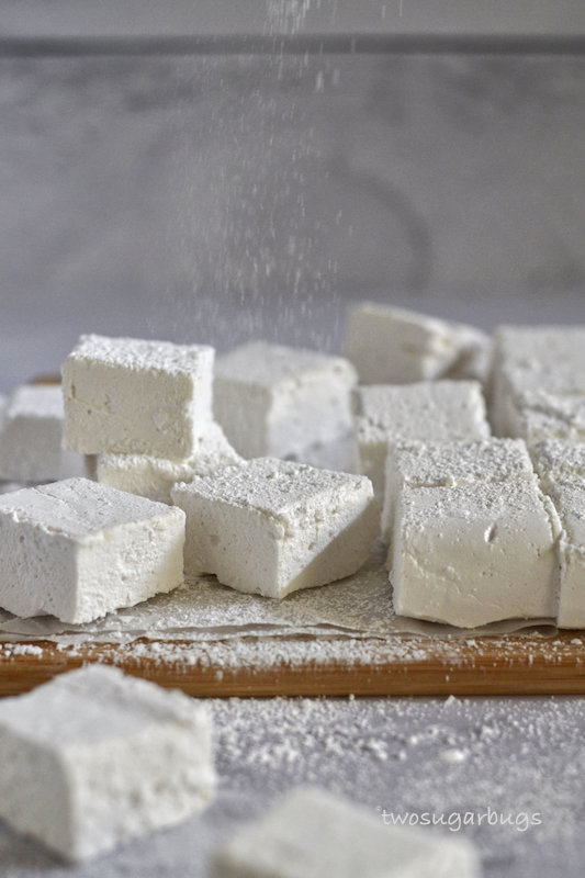 Powdered sugar being sprinkled on homemade marshmallows.
