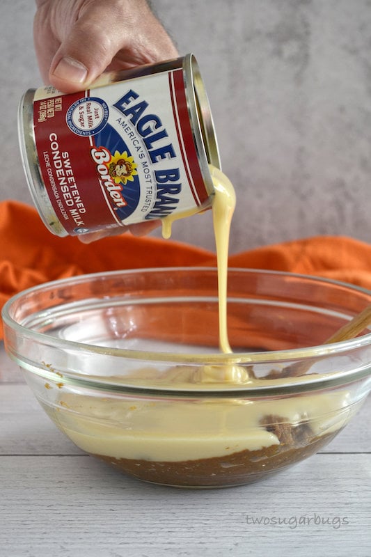 hand pouring Eagle Brand Sweetened Condensed milk into bowl