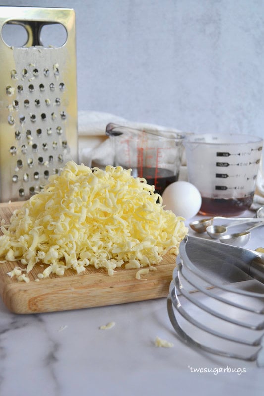 grated butter on a cutting board with pastry cutter and box grater in the background 