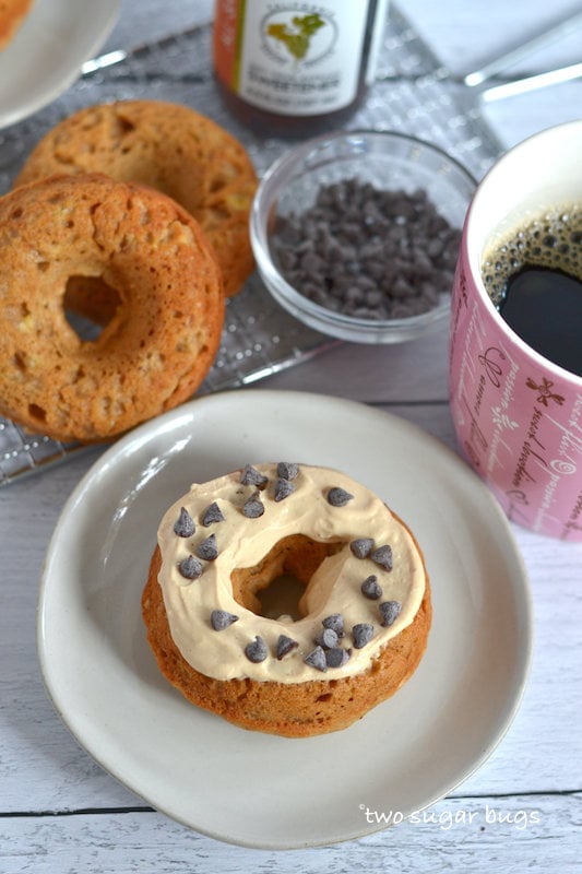 peanut butter glazed donut on a plate with plain donuts and coffee in the background