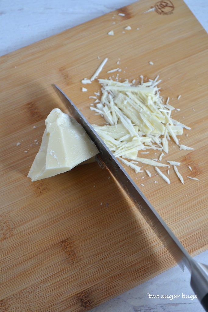 a knife chopping white chocolate on a cutting board