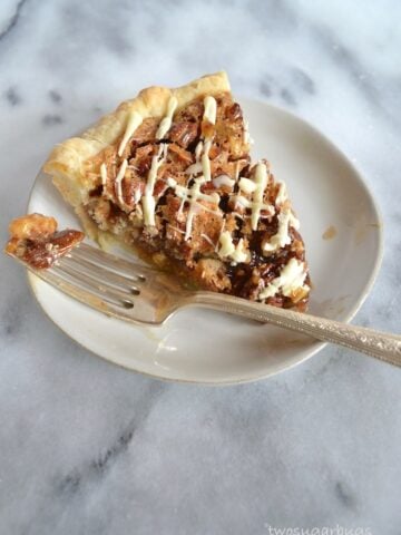 This white chocolate pecan pie is simple to prepare and sure to impress. It has a sweet and gooey center with chunky pecans and chunks of white chocolate. #twosugarbugs #pecanpie #thanksgivingpie #whitechocolate
