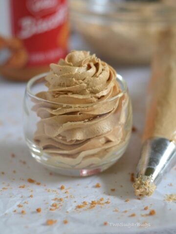 Piped cookie butter frosting in a glass with a piping bag next to it