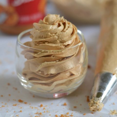 Piped cookie butter frosting in a glass with a piping bag next to it