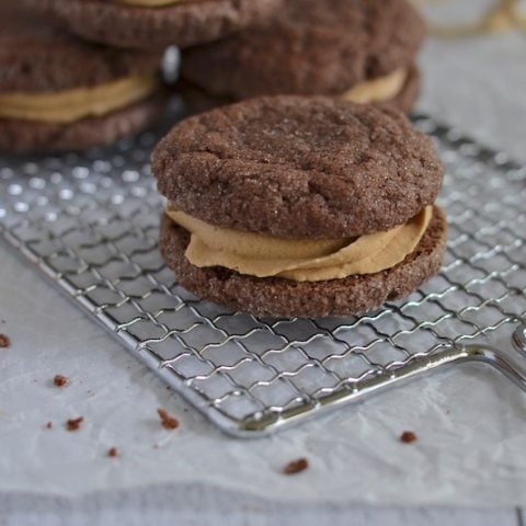 Chocolate Biscoff sandwich cookies on a wire rack.
