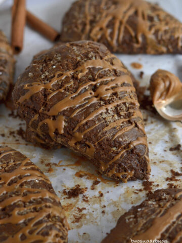 Gingerbread scones on parchment paper with a spoonful of Biscoff spread on the side