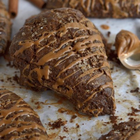Gingerbread scones on parchment paper with a spoonful of Biscoff spread on the side