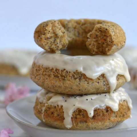 stack of three orange poppy seed donuts on a plate