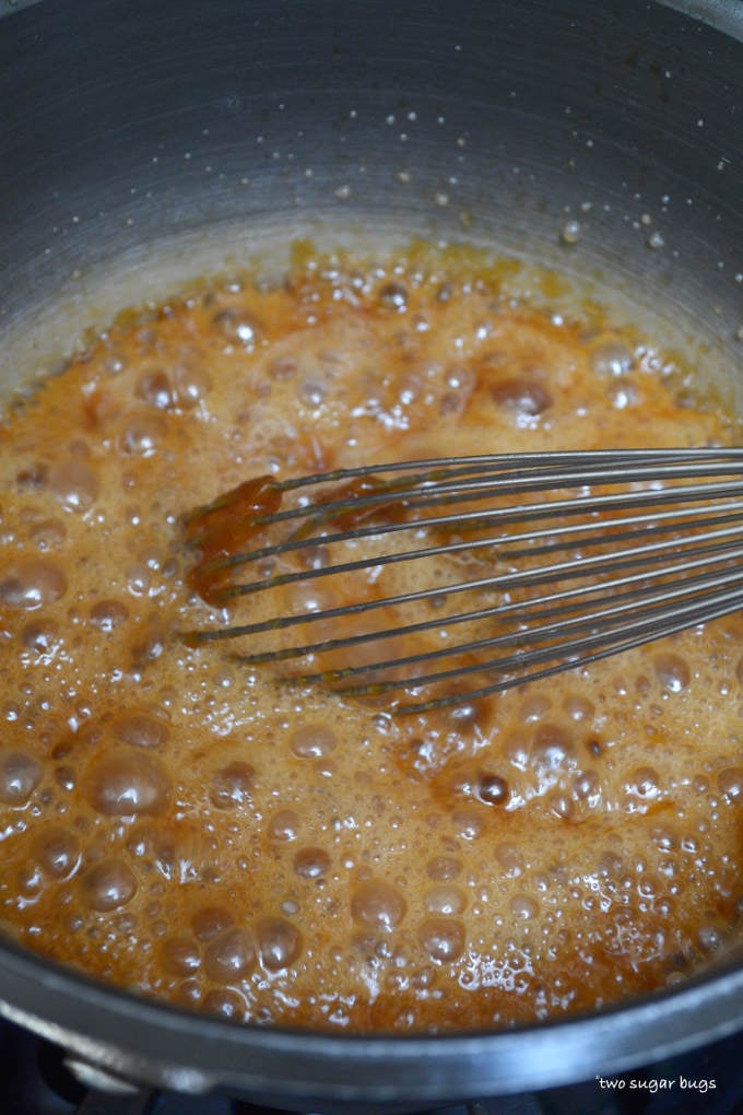boiling caramel in a sauce pan with a whisk