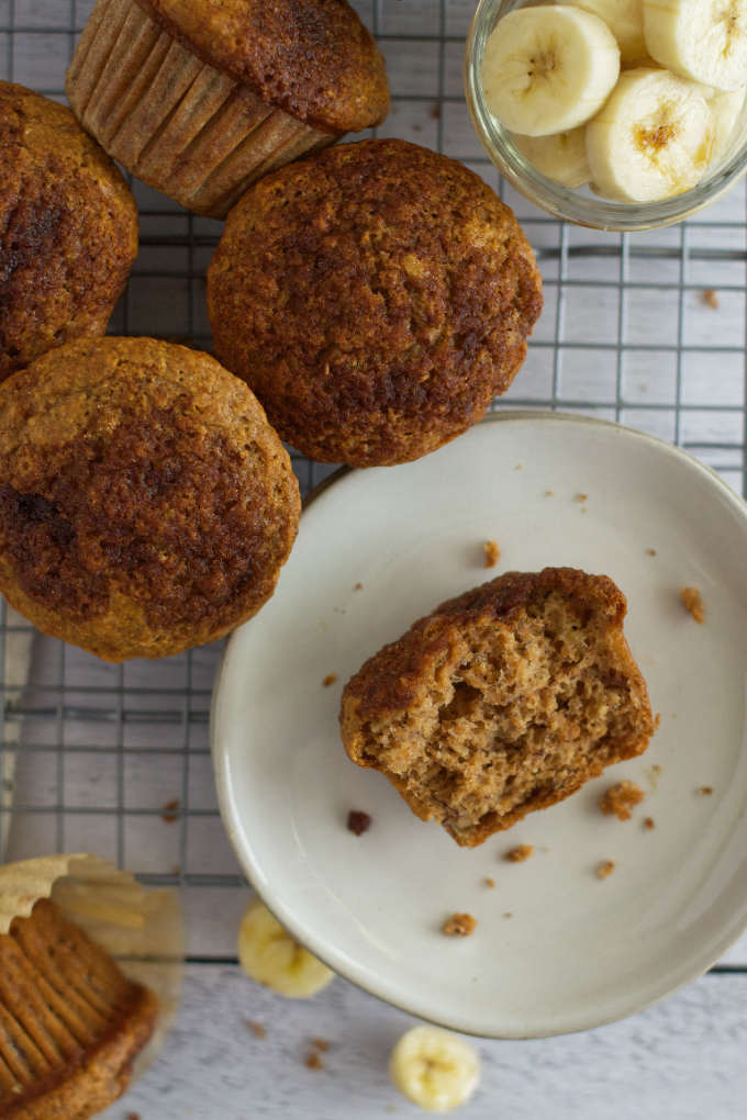 half a muffin on a plate surrounded by muffins and banana slices
