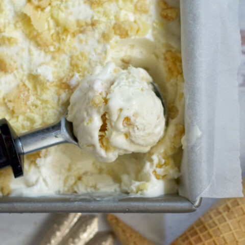 a scoop of lemon white chocolate cookie ice cream laying in the pan of ice cream