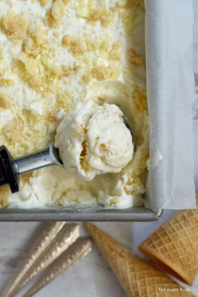 a scoop of lemon white chocolate cookie ice cream laying in the pan of ice cream