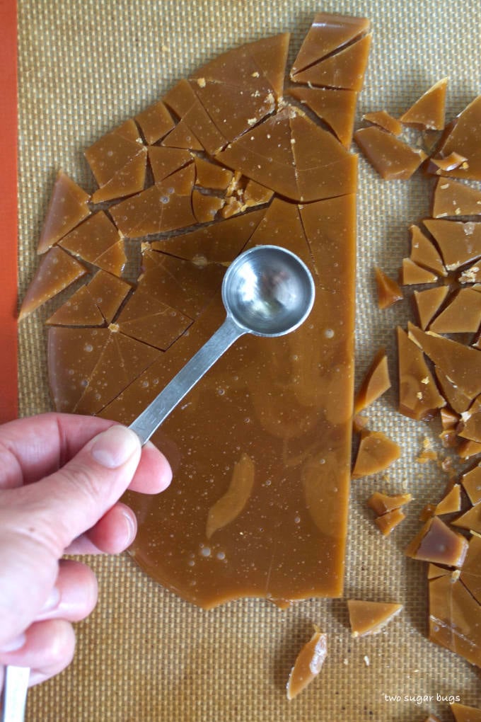homemade toffee on a silicone mat with a spoon cracking it