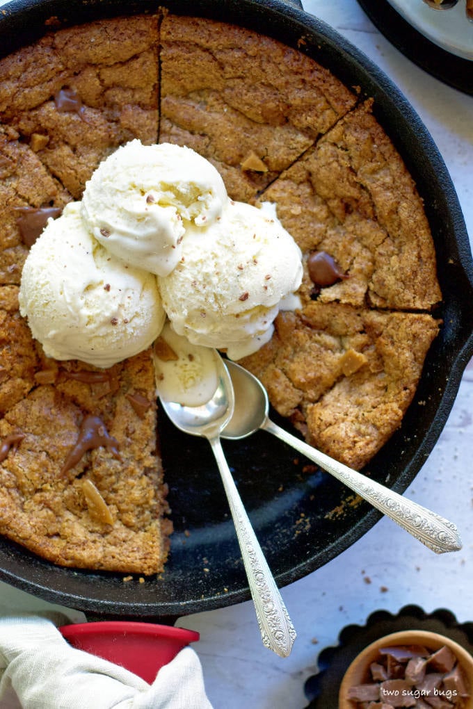 overhead shot of almond flour skillet cookie with three scoops ice cream and two spoons