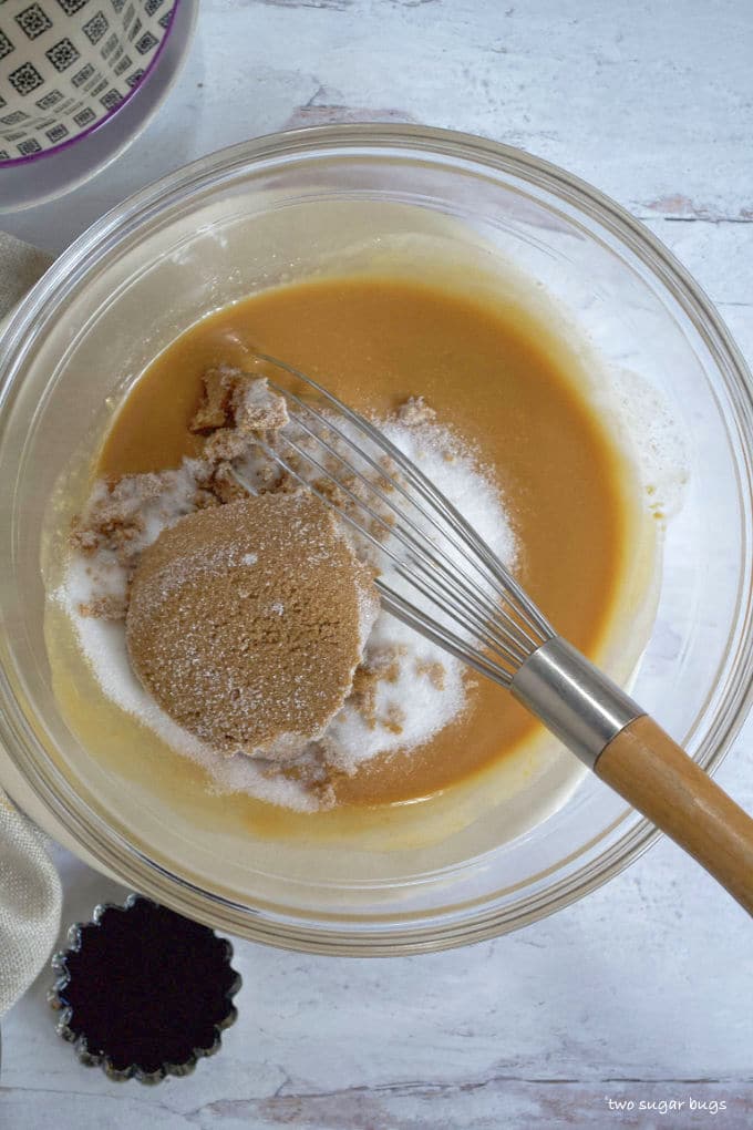 peanut butter and butter in a bowl with brown and granulated sugars and a whisk