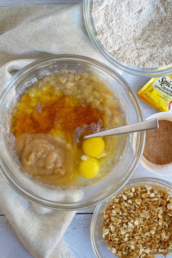 mashed bananas, applesauce, eggs and honey in a glass mixing bowl