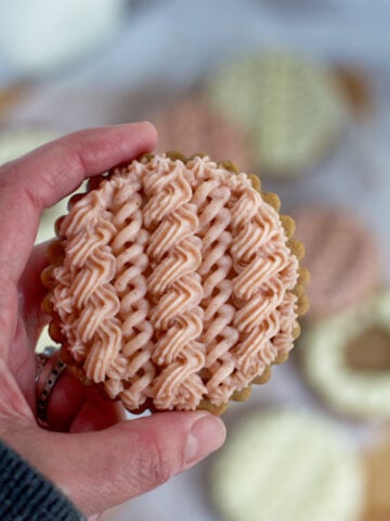 hand holding a cable knit sweater decorated sugar cookie