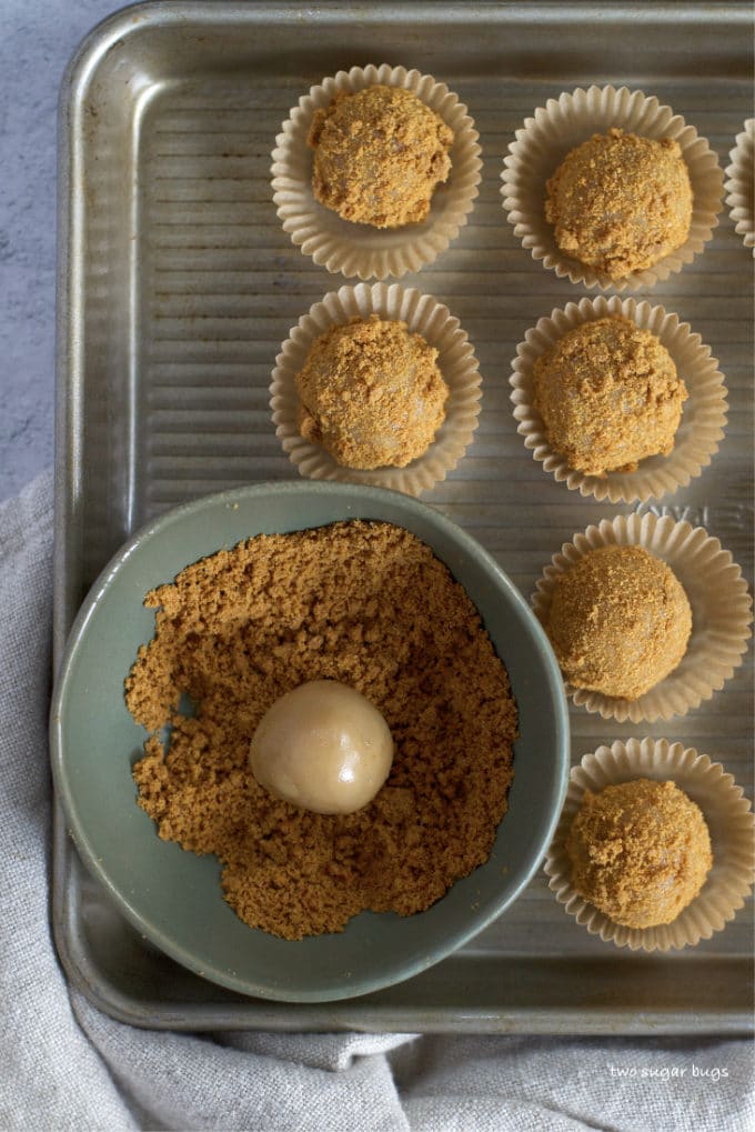 uncoated brigadeiro ball in bowl of crushed biscoff cookies