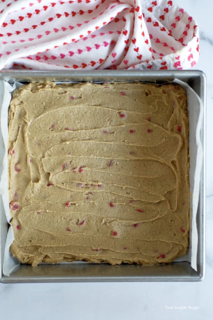 red hot cinnamon cookie bar dough in a parchment lined baking pan