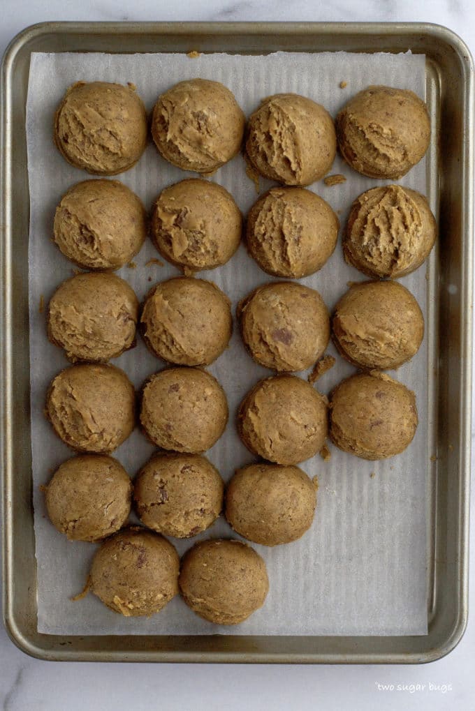 cookie dough scoops on a parchment lined baking sheet