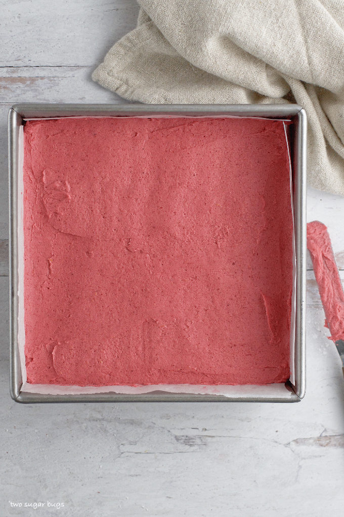 smoothed raspberry buttercream layer in a baking pan