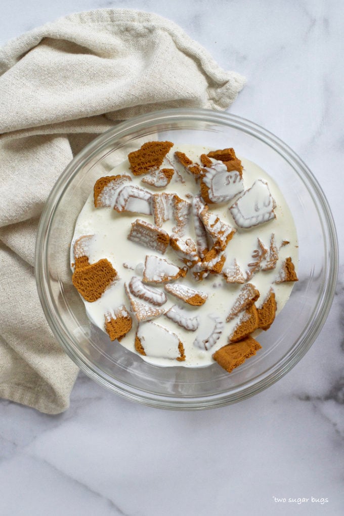 biscoff cookies and heavy cream soaking in a glass bowl