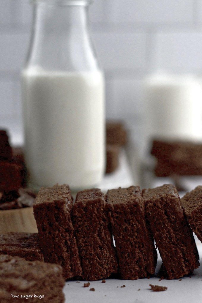 a row of brownies sitting with a carafe of milk