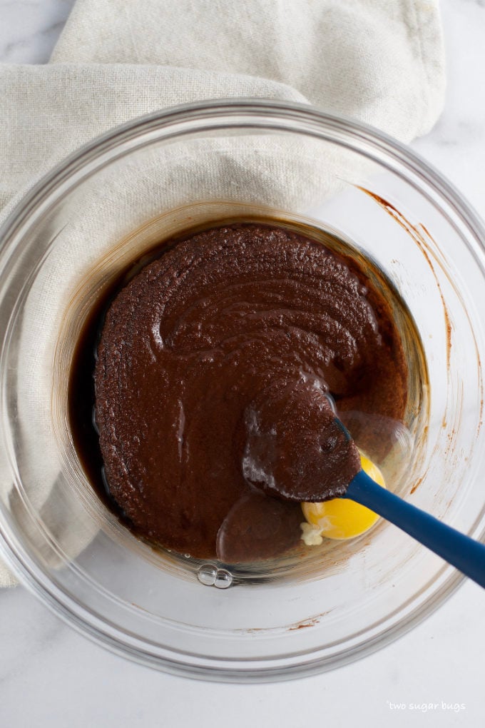 vanilla extract and an egg added to melted chocolate, butter and sugar in a bowl