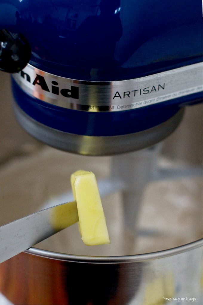 butter being added to the mixer with a knife