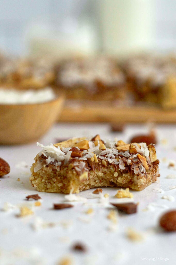 cookie bars with a bite out of it and bowl of coconut in the background