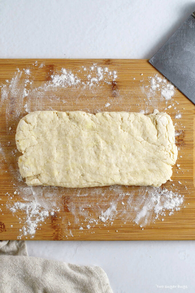 vanilla biscuit dough after being kneaded into a rough rectangle on a cutting board