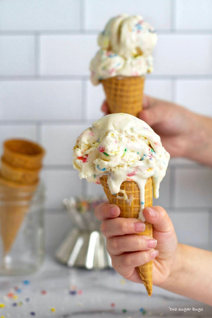two hands holding two melting ice cream cones