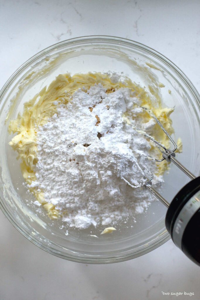 confectioners' sugar on top of creamed butter and cream cheese