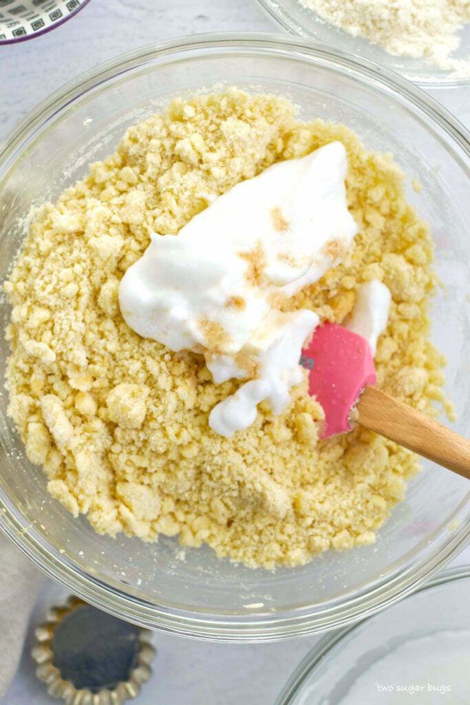 egg whites being added to almond flour and sugar