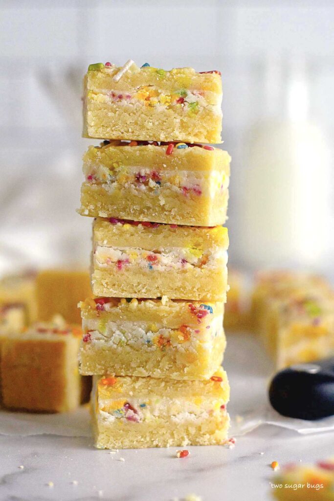 tall stack of sugar cookie bars stuffed with funfetti frosting