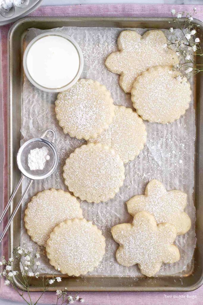 soft almond sugar cookies dusted with powdered sugar on a baking pan