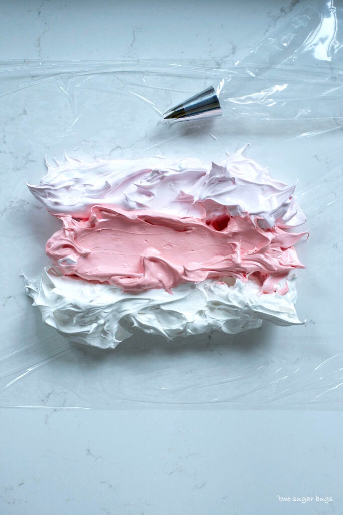 three colors of meringue on plastic wrap