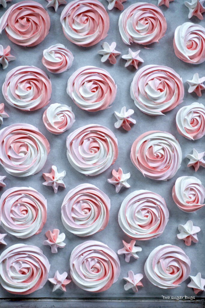 piped meringue cookies on a parchment lined baking sheet