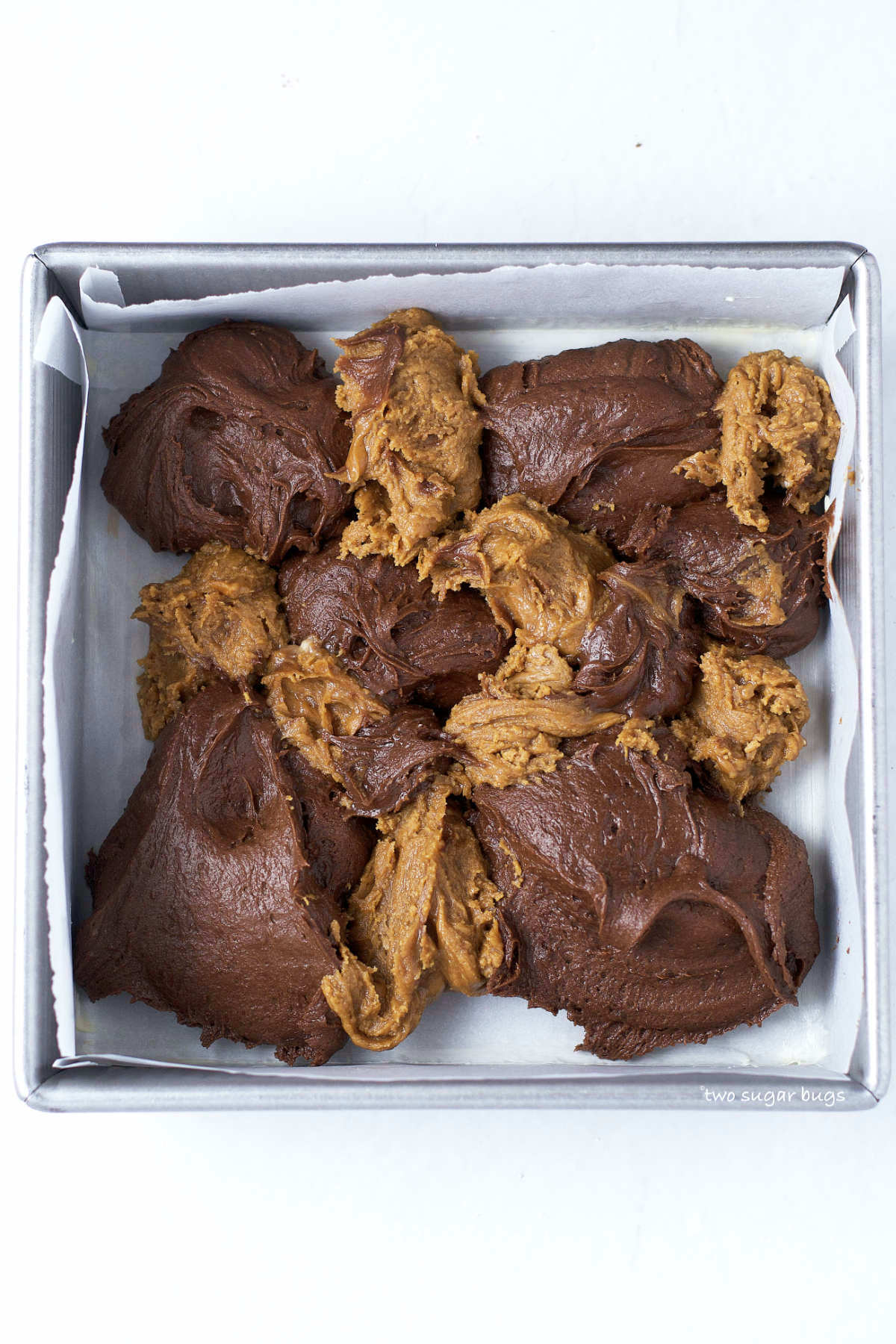 brownie batter and cookie butter fudge dropped into a baking pan