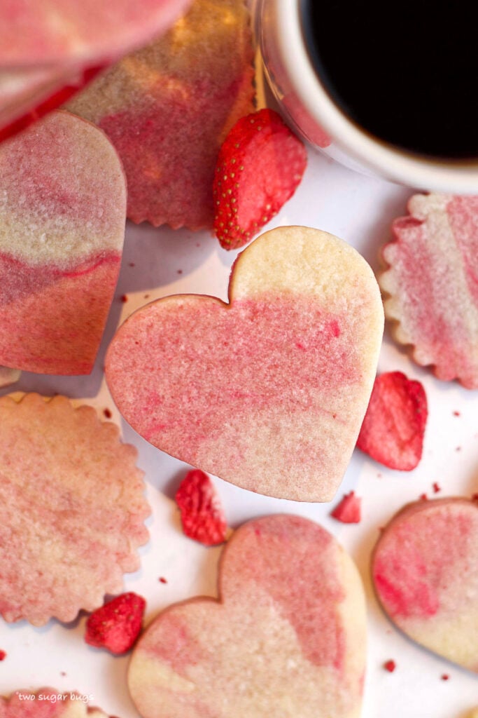 pink and white marbled sugar cookies with strawberries and a cup of coffee