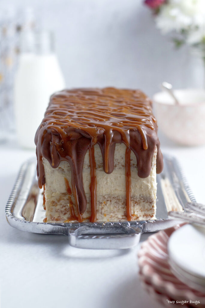 side view of a Twix cake with milk chocolate and caramel drips