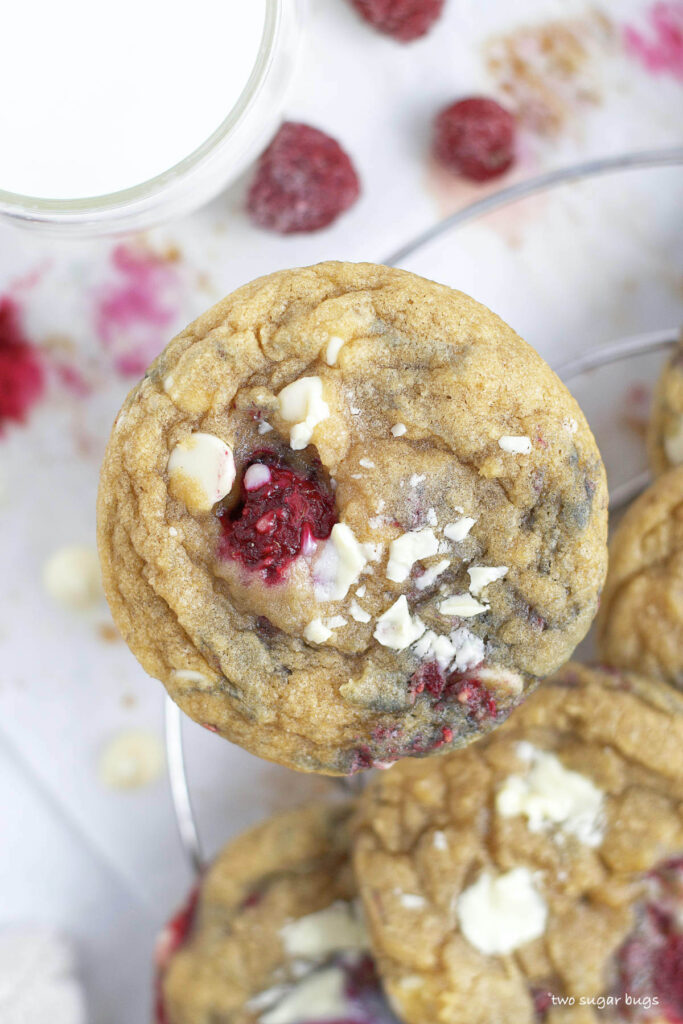 up close look at white chocolate raspberry cookies with a glass of milk