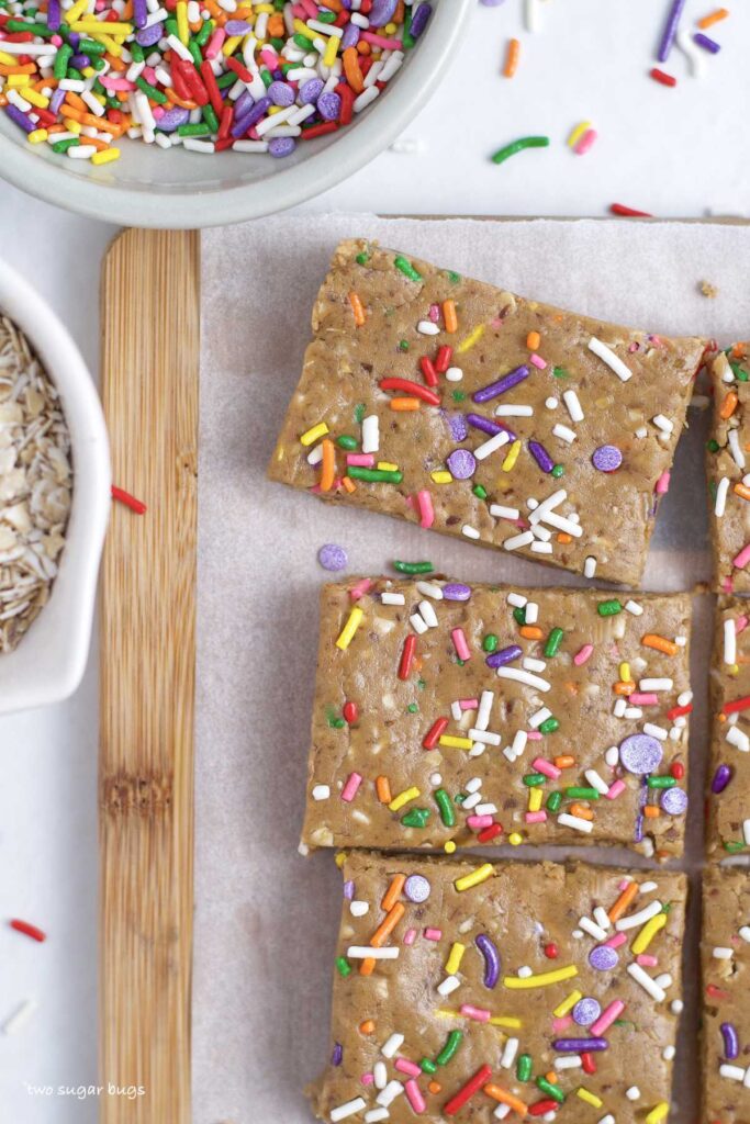 mini birthday cake protein bars with a bowl of oats and sprinkles