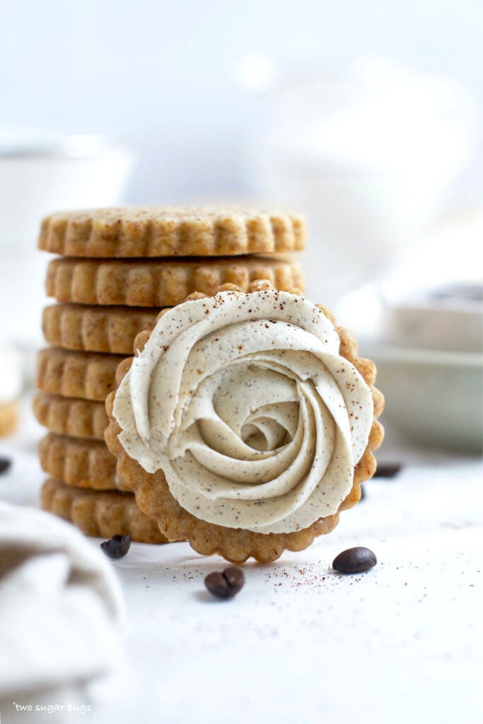 stack of cookies and one with a vanilla buttercream swirl